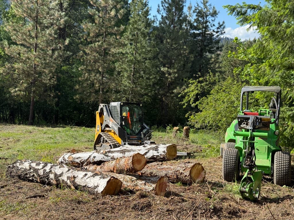 John Deere and Avant loaders with a pile of cut logs during site cleanup in the Upper Wenatchee Valley